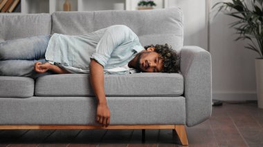 Yorgun Hintli çocuk kanepede kendini bitkin hissediyor. Depresyonda, motivasyon eksikliği, üzüntü, can sıkıntısı. Yorgunluktan, stresten kanepede yığılıp kalıyor. Söndür