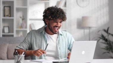 E-postalarını kontrol eden memnun Hintli adam ve iyi haberlerle mutlu. Kazanan genç adam zaferi kutluyor, ellerini yukarı kaldırıyor, kalemleri sallıyor.