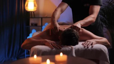 Masaj koltuğunda uzanan erkek eller, akşam atmosferinde masaj salonlarında tedavi edici boyun masajı yapıyor. Spa merkezinde puan masajı. Sağlıklı bir yaşam tarzı için vücut terapisi