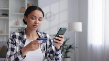 Masada otururken elinde cep telefonu ve kredi kartıyla gülümseyen Afro-Amerikan esmer bir kız. Cep telefonu ödemesini kullanarak internetten alışveriş yapan mutlu bir kadın. Elektronik bankacılık uygulaması