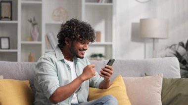 Tatmin olmuş Hintli adam koltukta oturmuş e-postalarını kontrol ediyor ve iyi haberlerle mutlu oluyor. Kazanan genç adam zaferi kutluyor masada oturuyor, ellerini yukarı kaldırıyor.