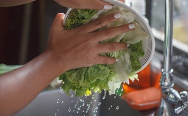 Adamın elleri mutfak lavabosunda sebze yıkıyor.