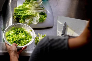 Kadın mutfakta taze sebze salatası hazırlıyor.