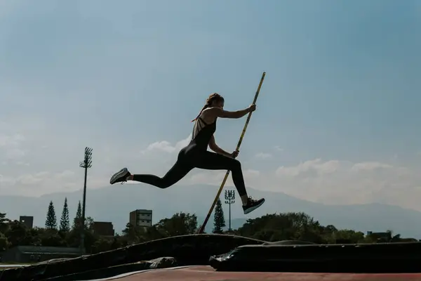 Young athlete woman on athletics track training pole vault