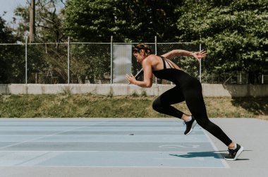 Genç atlet kadın atletizm pistinde koşuyor.