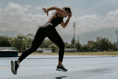 Genç atlet kadın atletizm pistinde koşuyor.