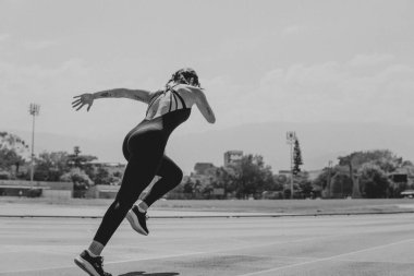 Genç atlet kadın atletizm pistinde koşuyor.