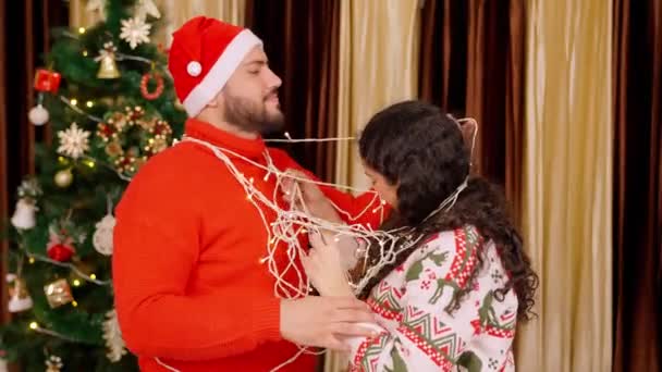 Happy Indian Couple Untangling Themself Ferry Lights Christmas Tree Background — Stock Video