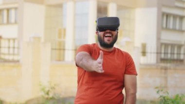 Kel Hintli Gülen Adam VR kulaklık takıyor, Sanal Gerçeklik kulaklığı takıyor.