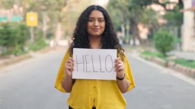 Kıvırcık saçlı Hintli Kız Merhaba Posteriyle Duruyor