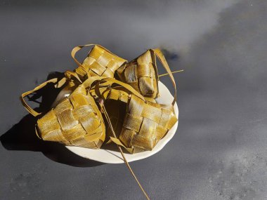 Olgun ketupat siyah arkaplanda bir tabakta mevcuttur