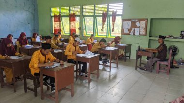 Sambas, Endonezya - 22 Mart 2024: İçeride değerlendirme soruları üzerinde çalışan lise öğrencileri