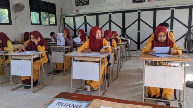 ambas, Endonezya-22 Mart 2024: içeride değerlendirme soruları üzerinde çalışan lise öğrencileri