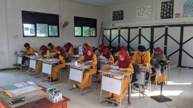 ambas, Endonezya-22 Mart 2024: içeride değerlendirme soruları üzerinde çalışan lise öğrencileri