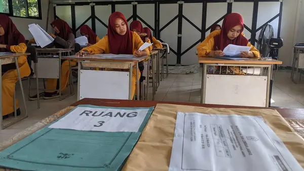ambas, Endonezya-22 Mart 2024: içeride değerlendirme soruları üzerinde çalışan lise öğrencileri