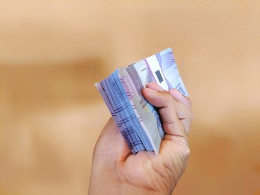 Çok sayıda on bin rupia tutan bir el.