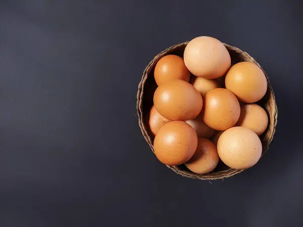 Siyah arka planda sepette tavuk yumurtası.