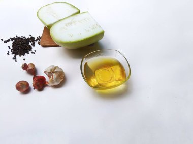 Water gourd fruit cut into pieces, edible oil, black marica, shallots and garlic on a white background clipart