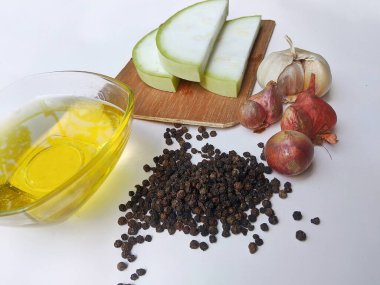 Water gourd fruit cut into pieces, edible oil, black marica, shallots and garlic on a white background clipart