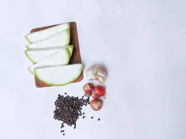 stock image Water gourd fruit cut into pieces, black marica, shallots and garlic on a white background