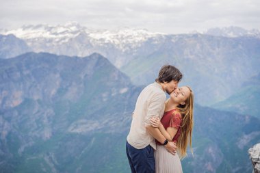 Erkek ve kadın, Karadağ 'daki Grlo Sokolovo boğazının nefes kesici panoramik manzarasının arka planında yaşayan mutlu çift turistler. Ön planda bir dağ var. Düz tarafı bir uçurum oluşturuyor.