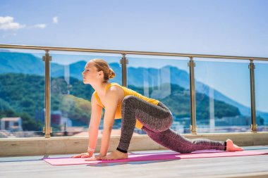 Güzel kadın bir çatı katı terasında açık havada yoga yaparken.