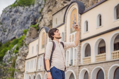 Karadağ 'ın Ostroska Greda kentindeki büyük kayanın tepesinde, Sırp Ortodoks Kilisesi' nin Ostrog Manastırı 'ndaki erkek turist. Ostrog 'lu Aziz Basil' e ithaf edilmiştir..