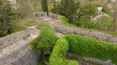 Yavaş çekim hava görüntüsü. Genç bir kadın ve oğlu turistler Herceg-Novi 'deki İspanyol kalesini veya Spanjola Kalesini ziyaret ediyorlar. Kalenin duvarlarında yürüyorlar. Karadağ 'a Seyahat.