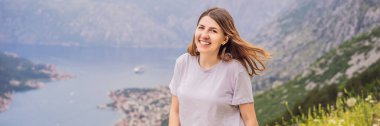 BANNER, LONG FORMAT Woman tourist enjoys the view of Kotor. Montenegro. Bay of Kotor, Gulf of Kotor, Boka Kotorska and walled old city. Travel to Montenegro concept. Fortifications of Kotor is on clipart