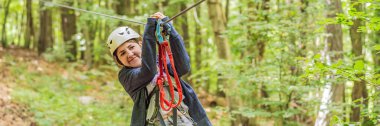 BANNER, BANNER, LONG FORMAT Mutlu kadın kız uçsuz bucaksız yol tramvaylarında tırmanıyor ağaçtaki karabina emniyet halatıyla ağaç tepesindeki halat macera parkına. Aile hafta sonu çocukları.