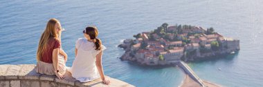 BANNER, LONG FORMAT İki Kadın turist arka planda güzel St. Stephen adası manzarası, Budva Riviera, Budva, Karadağ 'daki Sveti Stefan. Karadağ 'a Seyahat.