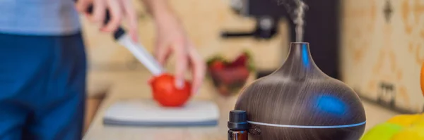 stock image BANNER, LONG FORMAT A man prepares food next to an aroma diffuser. cook cuts ripe red peppers in the kitchen. Cooking fresh, ripe, bell pepper salad for guests. Summer fresh vegetable salad.