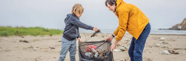 BANNER, LONG FORMAT Dad and son in gloves cleaning up the beach pick up plastic bags that pollute sea. Natural education of children. Problem of spilled rubbish trash garbage on the beach sand caused