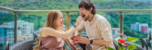 Couple feeding each other at breakfast eating strawberries. BANNER, LONG FORMAT