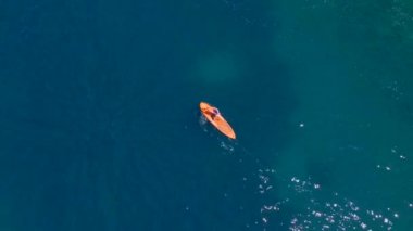 Ayakta duran genç bir kadın, kayaların arasında çırpınıyor. Açık mavi deniz suyu onu çevrelemiş. Hava yavaşlatıcı video.