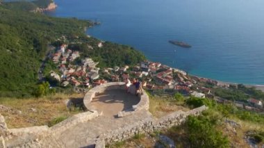 Bir grup arkadaş, Budva kenti yakınlarındaki Sveti Stefan adasının üzerindeki Saint Sava kilisesini ziyaret ediyor. Karadağ 'a Seyahat.