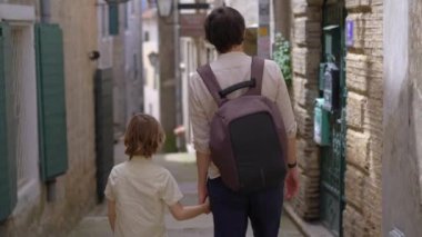 Karadağ 'ın kıyı kenti Herceg Novi' nin eski bir kasabasının sokaklarında genç bir adam ve oğlu yürüyor..