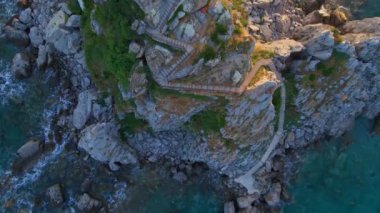Yavaş çekim hava görüntüsü. Sveta Nedelja - Petrovac şehrine yakın küçük bir adadaki Hristiyan kilisesi Adanın üzerinde bir sürü kukla uçar.