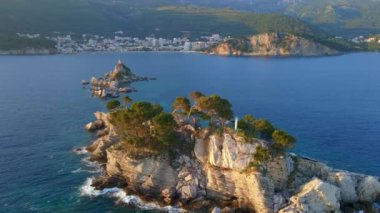 Yavaş çekim hava görüntüsü. Sveta Nedelja - Petrovac şehrine yakın küçük bir adadaki Hristiyan kilisesi Adanın üzerinde bir sürü kukla uçar.