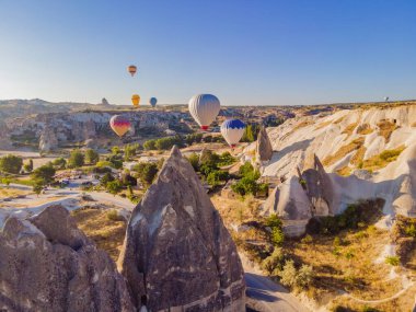 Nevsehir, Goreme, Kapadokya 'daki peri bacaları vadisinde uçan renkli sıcak hava balonları. Yeraltı şehri ve balonlu turizmin muhteşem panoramik görüntüsü. Yüksek kalite.