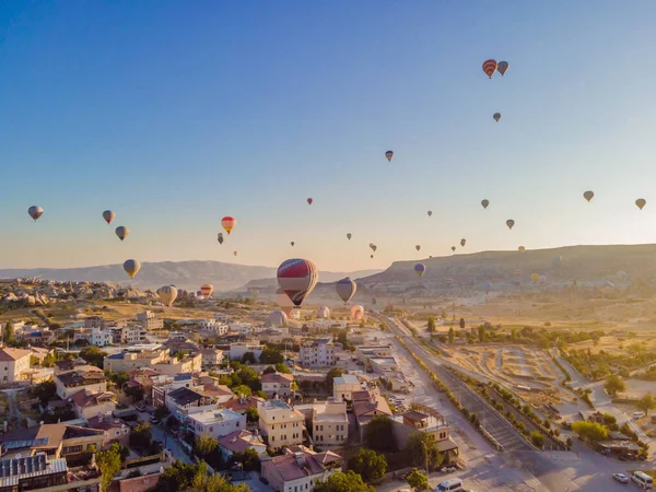 stock image Colorful hot air balloons flying over at fairy chimneys valley in Nevsehir, Goreme, Cappadocia Turkey. Spectacular panoramic drone view of the underground city and ballooning tourism. High quality.