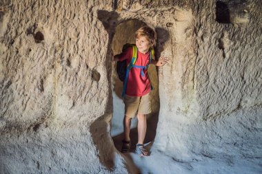 Kapadokya 'da Goreme yakınlarında kaya oluşumları ve peri mağaralarıyla vadiyi keşfeden çocuk turist..