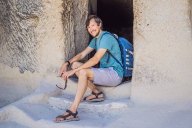 Kapadokya 'da Goreme yakınlarında kaya oluşumları ve peri mağaralarıyla vadiyi keşfeden genç adam.