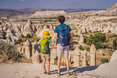 Baba ve oğul turistler Kapadokya 'da Goreme yakınlarında kaya oluşumları ve peri mağaralarıyla vadiyi keşfediyorlar..