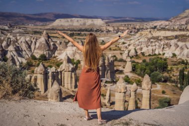 Kapadokya 'da Goreme yakınlarında kaya oluşumları ve peri mağaralarıyla vadiyi keşfeden genç bir kadın..
