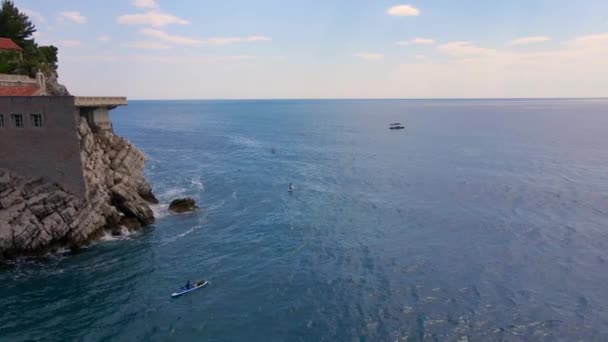 Vidéo aérienne ralentie. Jeune femme et son fils sur une planche SUP pagayer autour de l'île Sveti Stefan près de Budva. Été au Monténégro.