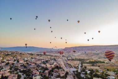 Nevsehir, Goreme, Kapadokya 'daki peri bacaları vadisinde uçan renkli sıcak hava balonları. Yeraltı şehri ve balonlu turizmin muhteşem panoramik görüntüsü. Yüksek kalite.