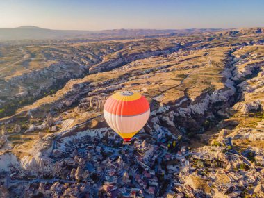 Nevsehir, Goreme, Kapadokya 'daki peri bacaları vadisinde uçan renkli sıcak hava balonları. Yeraltı şehri ve balonlu turizmin muhteşem panoramik görüntüsü. Yüksek kalite.