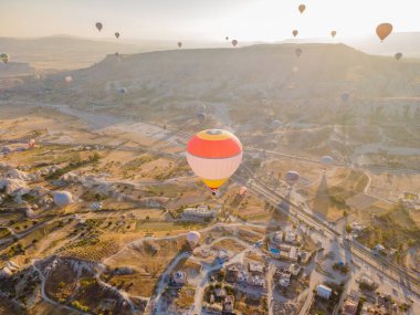 Nevsehir, Goreme, Kapadokya 'daki peri bacaları vadisinde uçan renkli sıcak hava balonları. Yeraltı şehri ve balonlu turizmin muhteşem panoramik görüntüsü. Yüksek kalite.