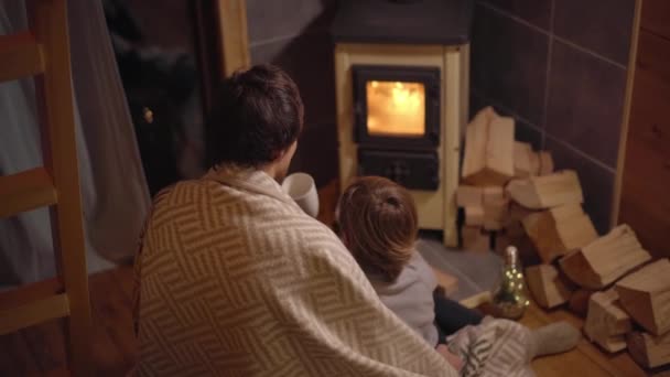 Młody Mężczyzna Jego Synek Zawinięci Koc Siedzą Przy Domowym Piecu — Wideo stockowe